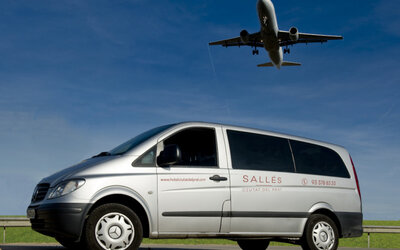 Silver Mercedes passenger van displaying hotel branding beneath a clear blue sky at Hotel Sallés Ciutat del Prat.