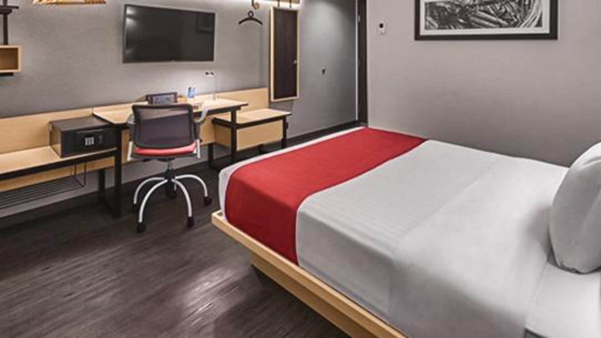 Guest room with a double bed, red runner, wall-mounted television, wooden desk and shelving at City Express by Marriott CDMX La Villa.
