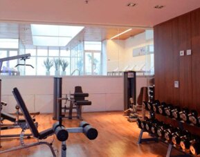 Fitness centre with weight machines, adjustable benches and dumbbell racks beside wooden flooring at Design Suites Buenos Aires.
