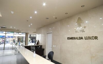 Hotel reception with marble counter, black workstation and wall-mounted HR Hotel Esmeralda Luxor signage.