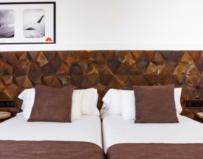 Guest room with white bed linens, brown accent cushions, geometric padded headboard and bedside tables at Hotel Best Western PLUS Alfa Aeropuerto.