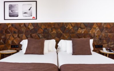 Guest room with white bed linens, brown accent cushions, geometric padded headboard and bedside tables at Hotel Best Western PLUS Alfa Aeropuerto.