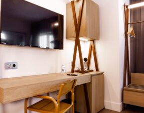 Guest room workspace with wooden desk, chair, wall-mounted television, open wardrobe and hanging clothes at Hotel Best Western PLUS Alfa Aeropuerto.