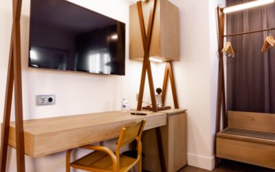 Guest room workspace with wooden desk, chair, wall-mounted television, open wardrobe and hanging clothes at Hotel Best Western PLUS Alfa Aeropuerto.
