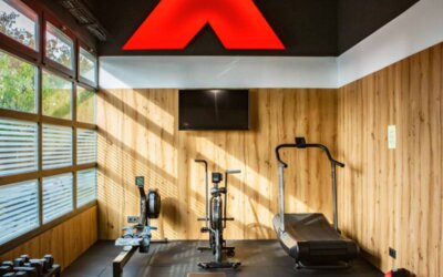 Fitness room with exercise machines, dumbbells, wooden wall panels and large windows at Hotel Best Western PLUS Alfa Aeropuerto.