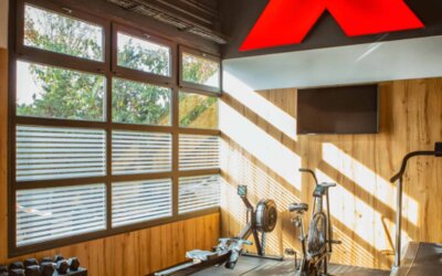 Gym with treadmill, stationary bikes, weight bench and dumbbells in a wood-panelled room at Hotel Best Western PLUS Alfa Aeropuerto.