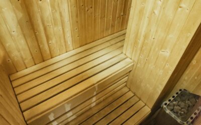 Wooden sauna with tiered benches and a stone heater in the corner at Hotel Best Western PLUS Alfa Aeropuerto.