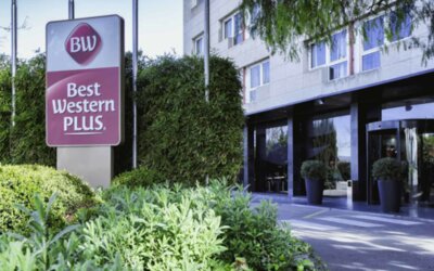 Modern hotel exterior with Best Western PLUS signage, glass entrance and landscaped greenery at Hotel Best Western PLUS Alfa Aeropuerto.