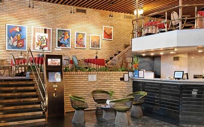 Reception area with black front desk, staircase, brick walls and small round tables with chairs at Hotel Regente Palace.