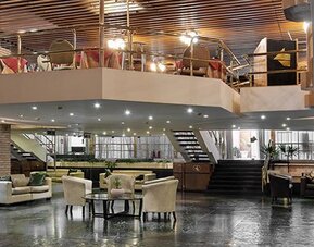 Spacious lobby with leather lounge seating, reception area, staircase and upper-level balcony at Hotel Regente Palace.