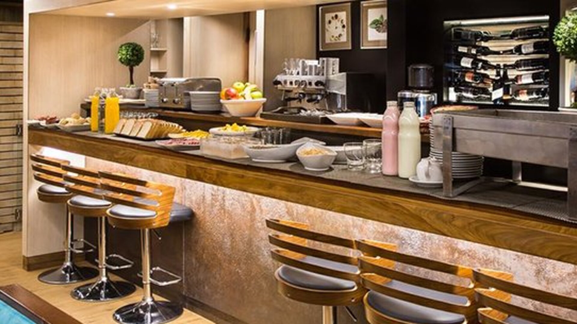 Hotel bar with long wooden counter, bar stools, illuminated bottle displays and polished wood finishes at Hotel Regente Palace.