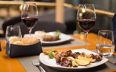 Restaurant table set with plated food, bread rolls, wine glasses and folded napkins at Hotel Regente Palace.