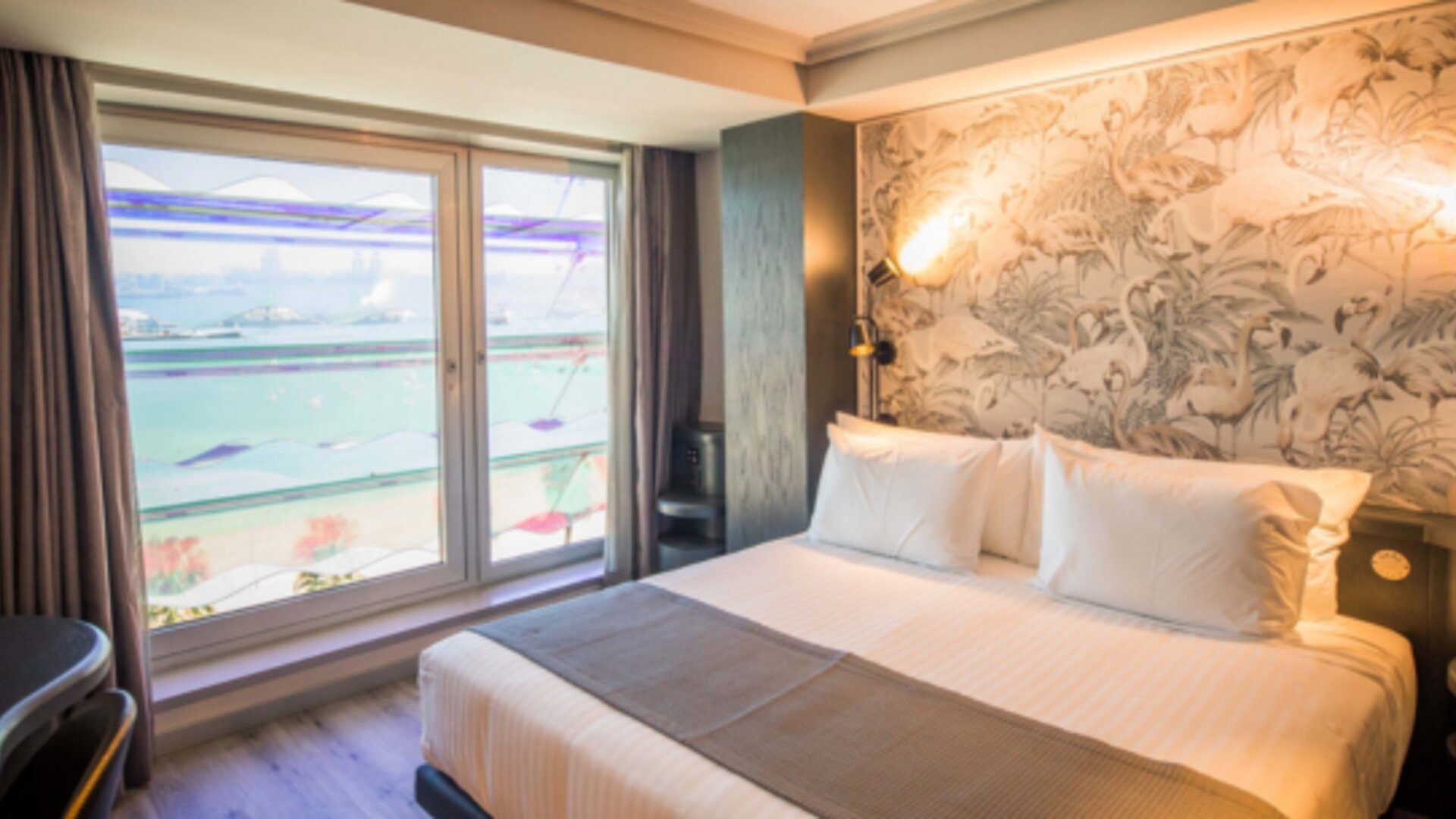 1. Guest room with king bed, patterned feature wall and large window overlooking the beach and sea at Hotel Silken Saaj Las Palmas.