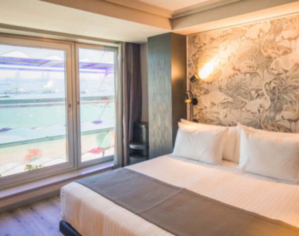 1. Guest room with king bed, patterned feature wall and large window overlooking the beach and sea at Hotel Silken Saaj Las Palmas.