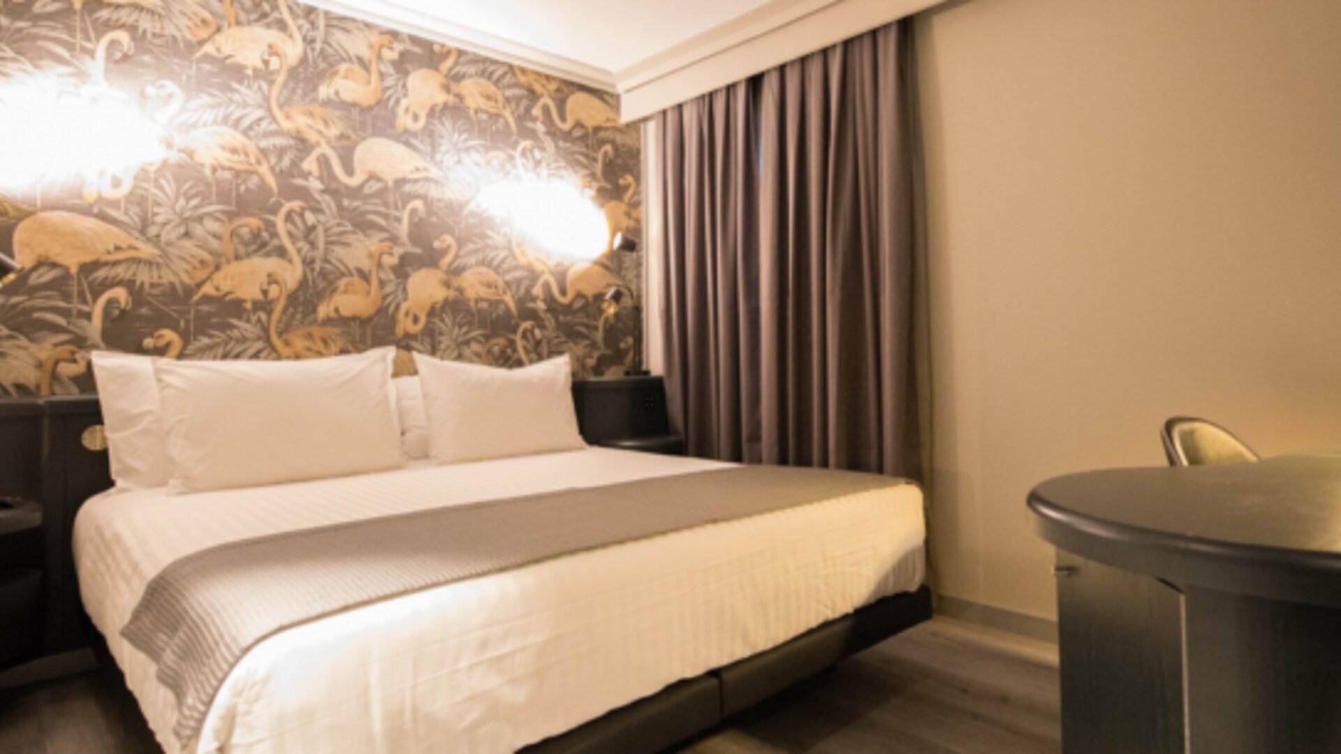 King bed with white linens, grey runner, patterned decorative headboard and warm bedside lights at Hotel Silken Saaj Las Palmas.