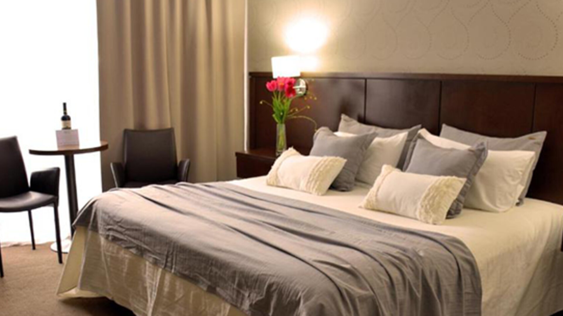 Guest room with a king bed, grey runner, layered pillows, bedside tables and warm lighting at Ian Hotel.