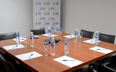 Meeting room with wooden conference table, black chairs, bottled water, glasses and notepads at Ian Hotel.