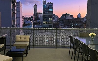 Rooftop terrace with lounge seating, dining table and city skyline views at sunset at Ian Hotel.