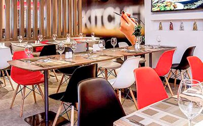 Restaurant with wooden tables, red and white chairs, place settings and decorative wall panels at Ibis Lima Reducto Miraflores.