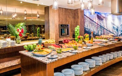 Breakfast buffet with fresh fruit, pastries, stacked plates and serving counters under pendant lighting at Hospedium Princess Hotel Panamá.