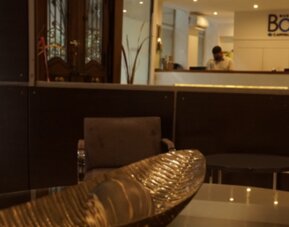 Reception lounge with dark partition, upholstered chairs, decorative bowl and reception desk in the background at Bagu Buenos Aires.