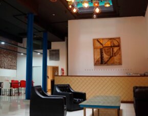Lounge area with black sofas, low coffee table, blue support columns and colorful pendant lighting at Bagu Buenos Aires.
