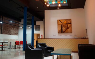 Lounge area with black sofas, low coffee table, blue support columns and colorful pendant lighting at Bagu Buenos Aires.