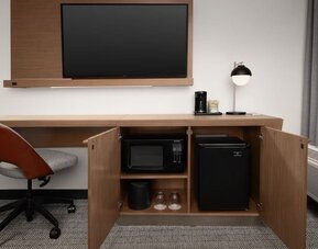 Guest room work area with wall-mounted television, wooden desk, office chair, microwave and mini refrigerator at Courtyard By Marriott Dothan.