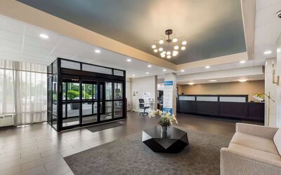 Hotel lobby with reception desk, glass entrance, seating area and decorative coffee table at Best Western Executive Hotel Of New Haven-West Haven.
