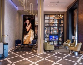 Stylish hotel lounge with armchairs, seating areas, bookshelves and a large decorative portrait at David Tower Hotel Netanya.
