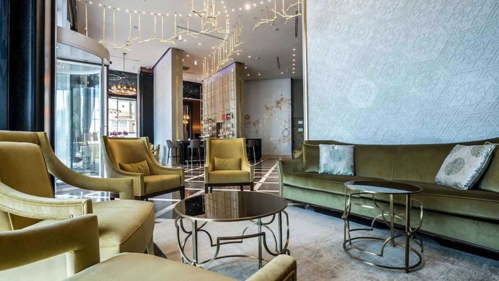 Lobby seating area with olive-green armchairs, a matching sofa, round coffee tables and decorative lighting at David Tower Hotel Netanya.