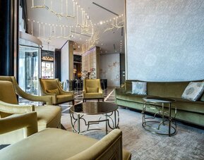 Lobby seating area with olive-green armchairs, a matching sofa, round coffee tables and decorative lighting at David Tower Hotel Netanya.