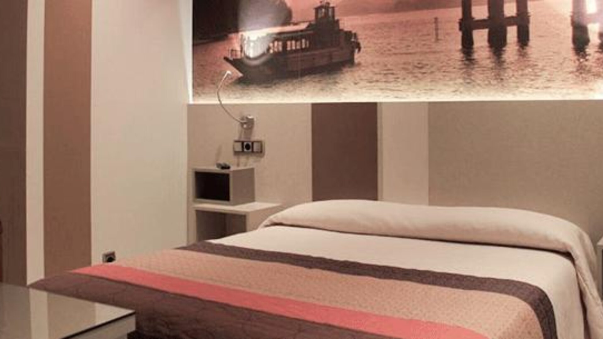 Double bed with white bedding, a red and brown runner, bedside tables and framed waterfront artwork at Hostal Atocha Almudena Martín.