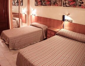 Twin room with two single beds, matching striped bedspreads, bedside tables, wall lights and a full-length mirror at Hostal Atocha Almudena Martín.