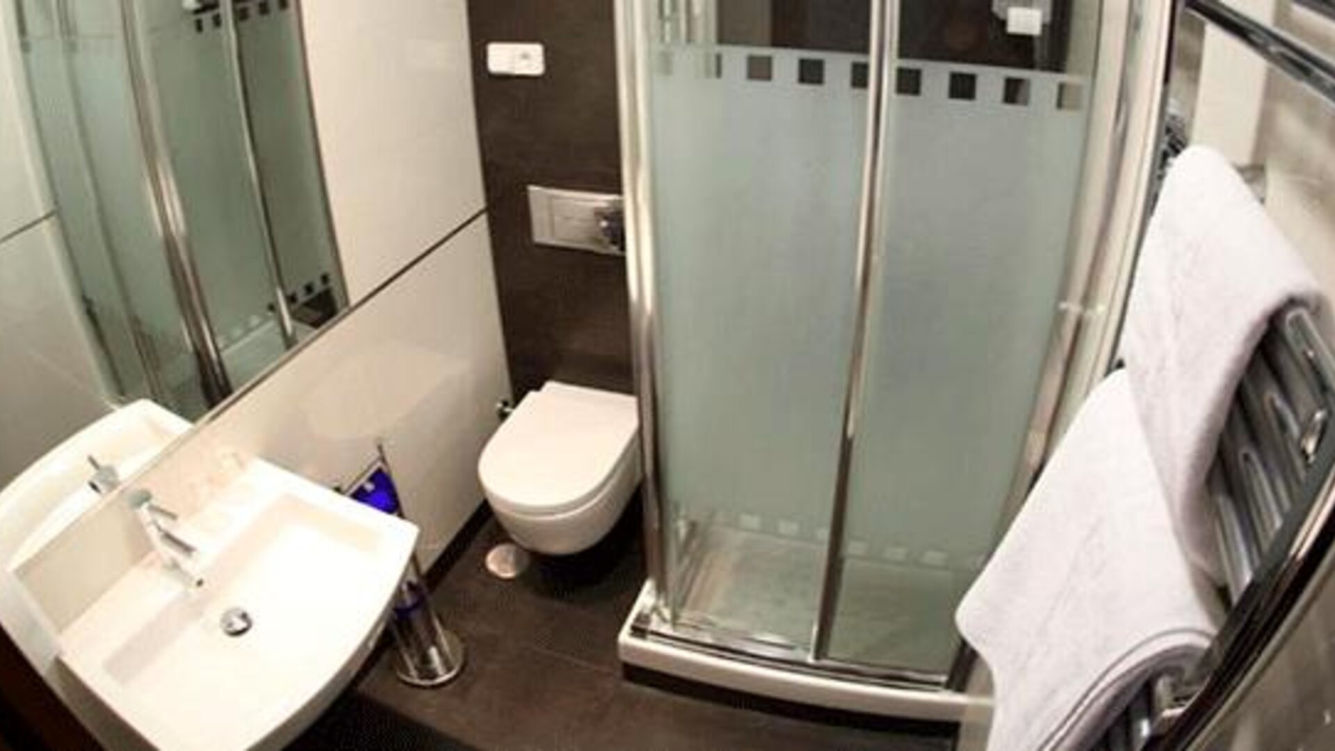 Compact bathroom with a white sink, toilet, glass-enclosed shower and chrome towel rail at Hostal Atocha Almudena Martín.