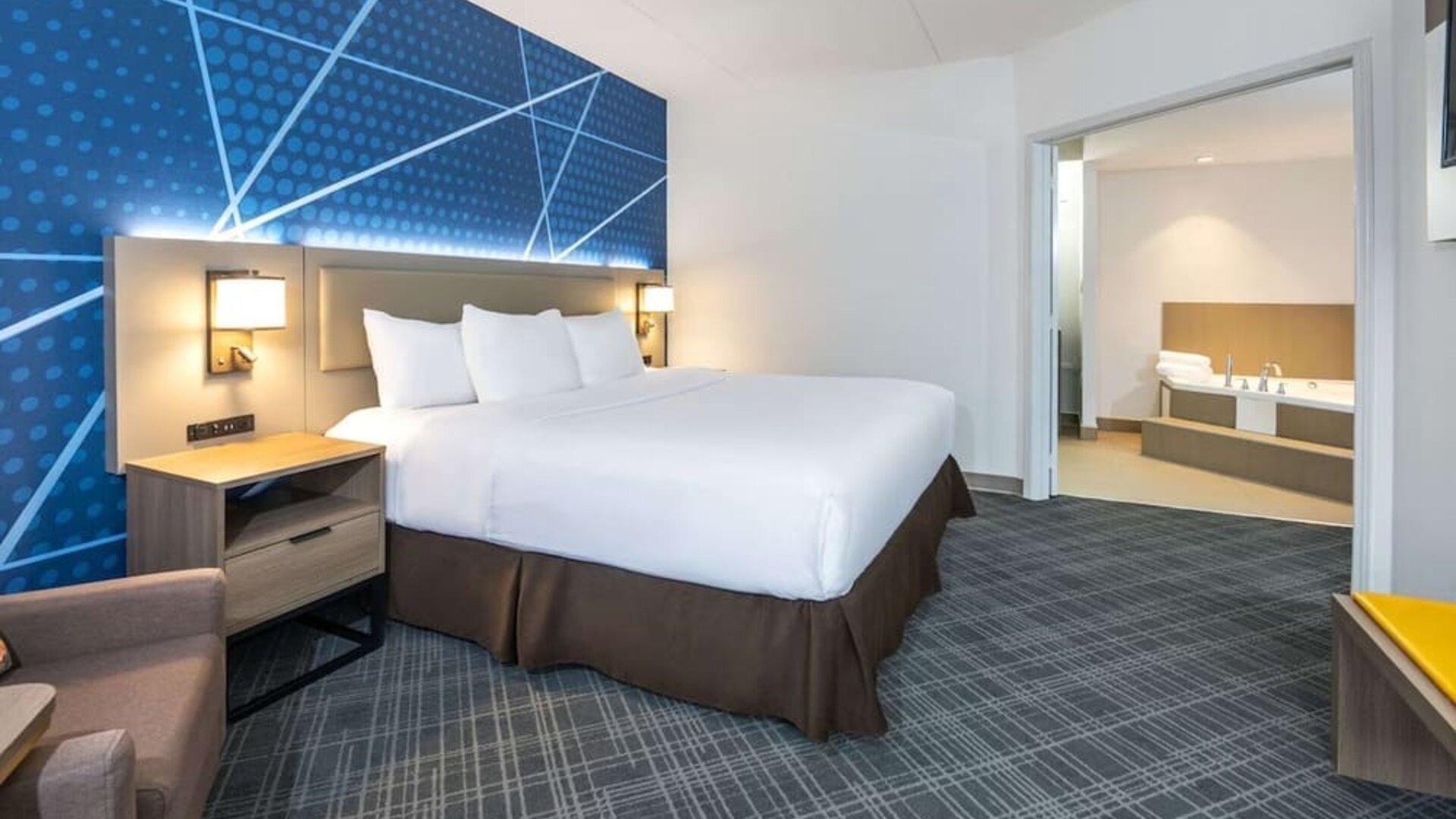 Day use king suite with comfortable bed, sofa and private bathroom with tub at Comfort Inn & Suites Barrie. 