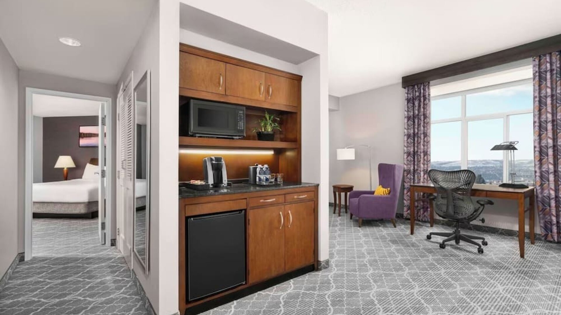 View of entire deluxe suite; king size bed, kitchenette, and area with desk for work at Hilton Garden Inn Calgary Airport.