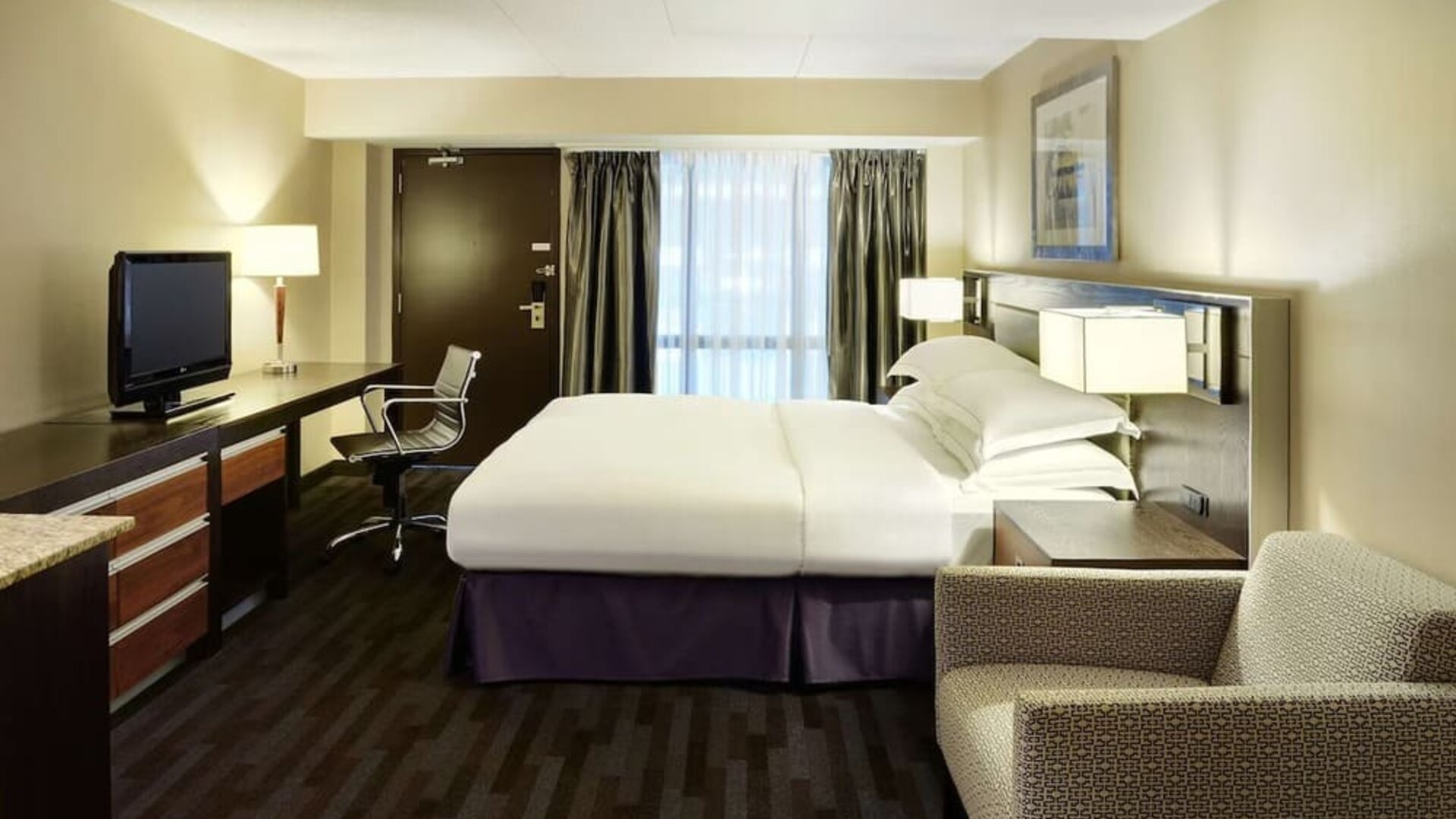 Day use room with TV, work desk, lounge area and private bathroom at Hilton Winnipeg Airport Suites.