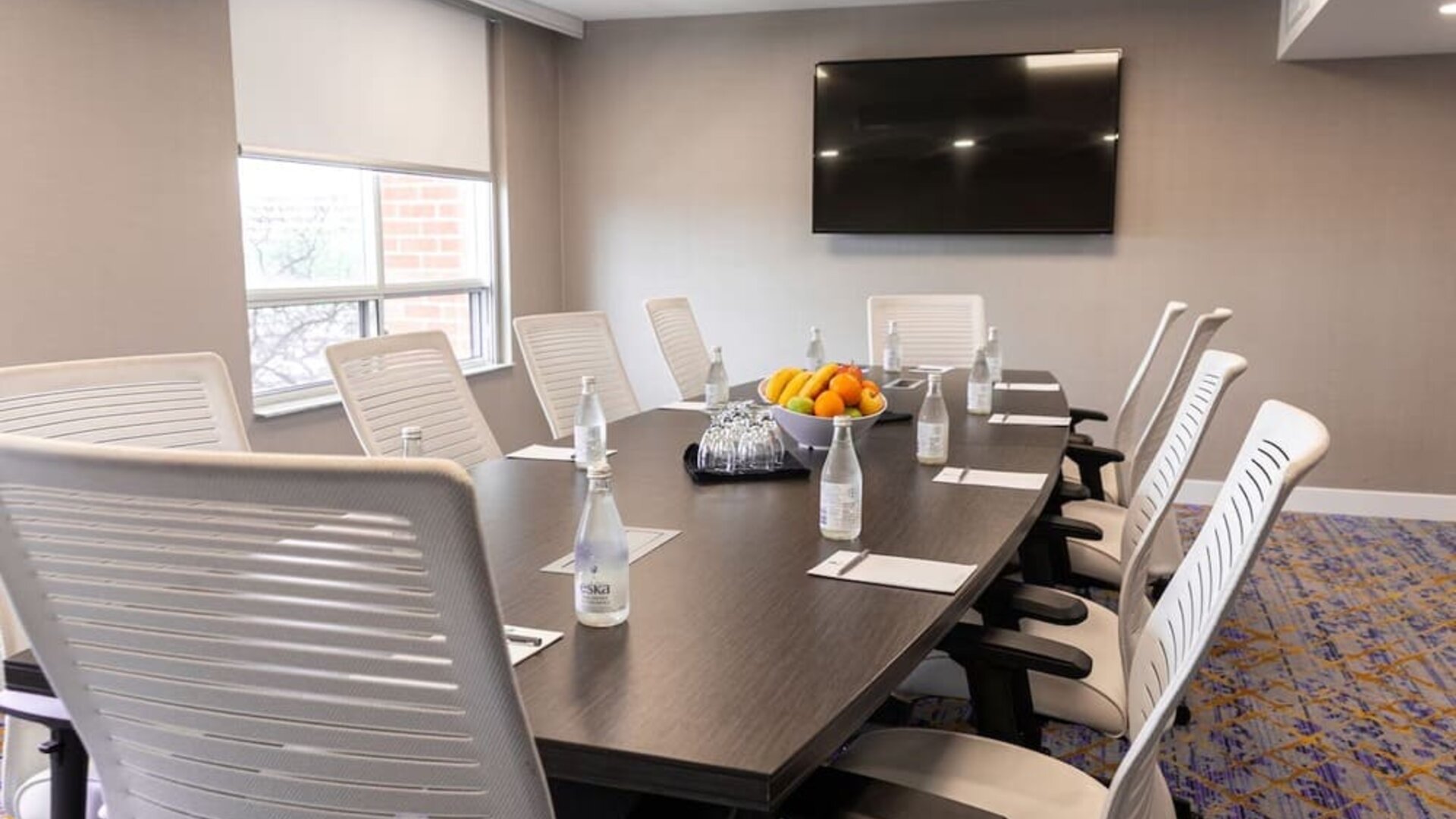 Professional meeting room with TV screen and ergonomic chairs at the Embassy Suites By Hilton Toronto Airport.