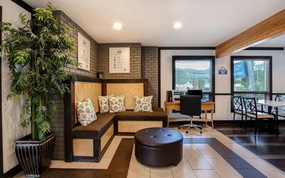 Hotel lobby with lounge area and workspace with computer and printer at Days Inn Vernon.