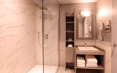 Guest bathroom with shower and free toiletries at Le Chabrol Hotel Et Suites.