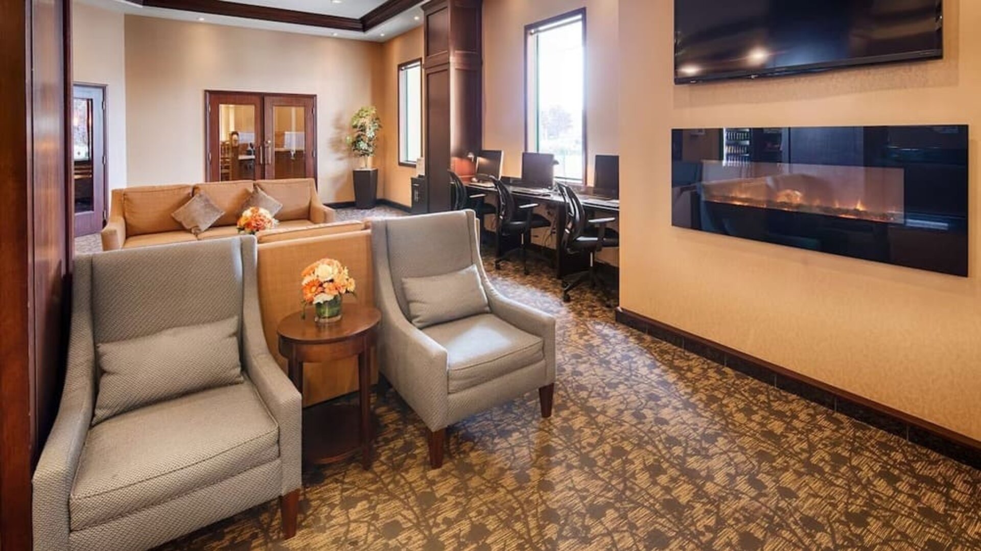 Comfortable lobby lounge with fireplace and workspace with computers, printer and ergonomic chairs at Best Western Plus Winnipeg Airport.