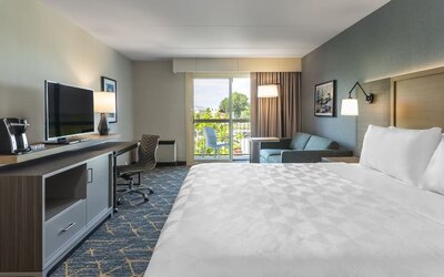 Day use room with TV, work desk, living area and balcony at Holiday Inn Kingston Waterfront.