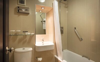 Guest bathroom with tub and free toiletries at Thistle London Heathrow Terminal 5.