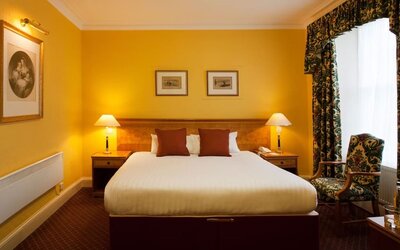 Single bed guest room in The Royal Highland Hotel, with bedside lamp and art on the wall.