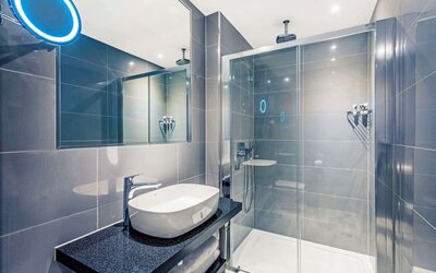 Guest bathroom with shower at Mercure Hotel London Hyde Park.