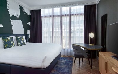Bright and spacious day use room with king bed, TV screen and work desk at NYX Hotel London Holborn By Leonardo.