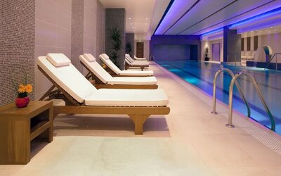 Relaxing indoor heated pool with comfortable lounge chairs at Leonardo Royal Hotel London Tower Bridge.