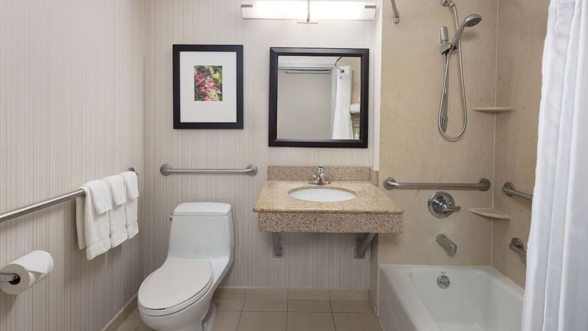Guest bathroom with shower and tub at Hilton Garden Inn Queens/JFK Airport.