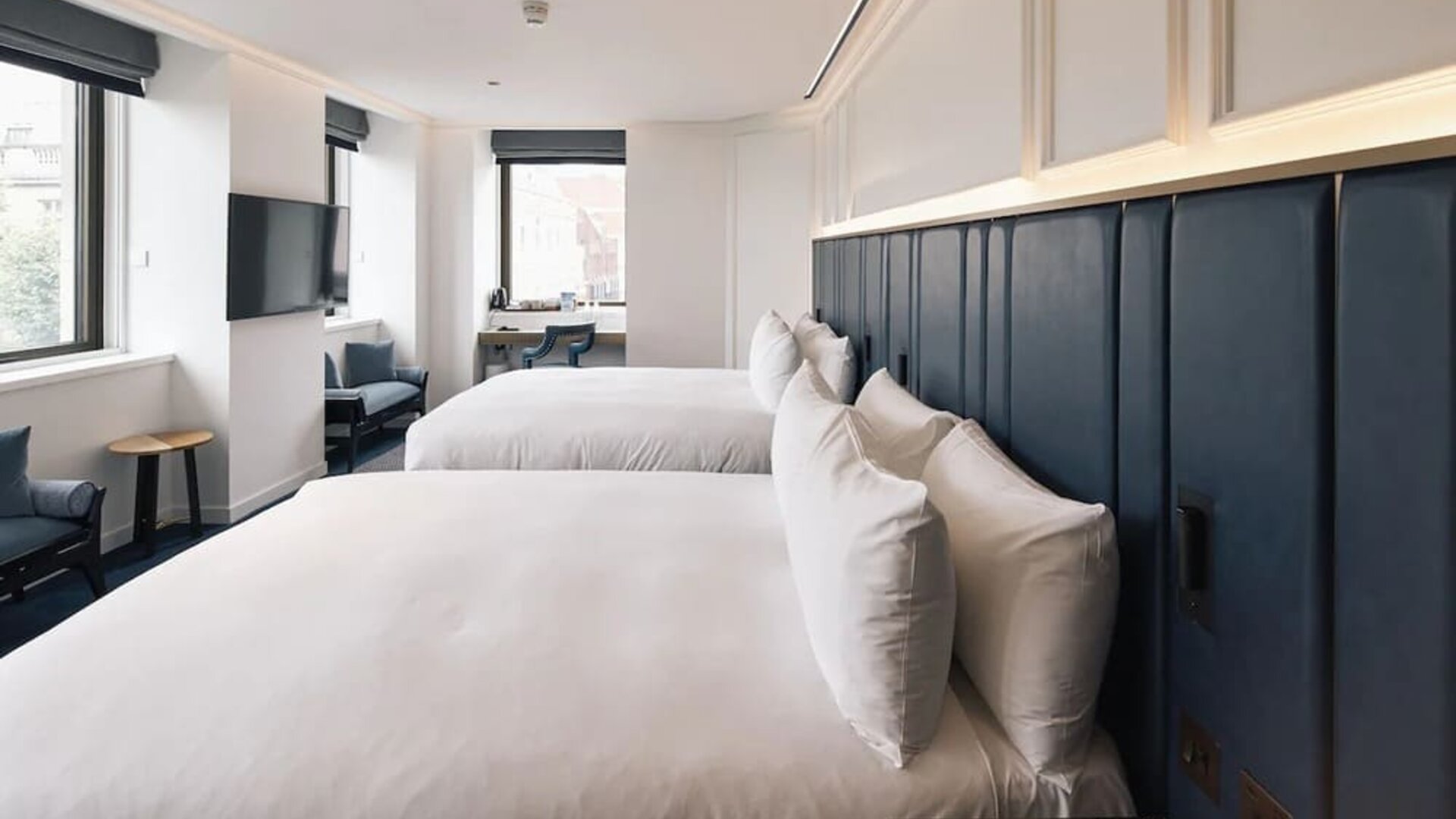 Family room with two king beds, TV screen, work desk and lounge seating at Page8, Page Hotels.